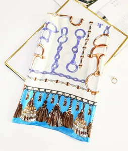 Detail of silk scarf with golden horsebit buckle, chain patterns and blue tassels