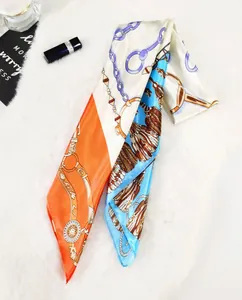 Detail of 90cm silk scarf featuring horseshoe chain and tassel patterns on plush background