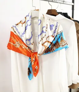 Detail of a 90cm square scarf with horse-chain and tassel prints tied on a white shirt