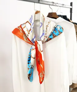 Detailed view of the silk scarf featuring horse-bit chains and tassels on a white shirt