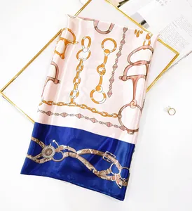 Detail of luxury silk scarf with gold chain and horseshoe print in blue and pink tones