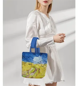 Detail of Van Gogh Wheatfield print tote bag with blue handles held by a model
