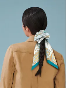 Detail of a yellow and blue geometric twilly scarf tied as an elegant ponytail ribbon