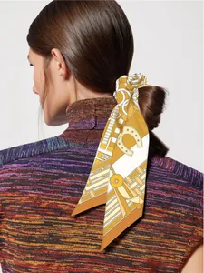 Detail of silk hair scarf with orange equestrian print tied on a low ponytail