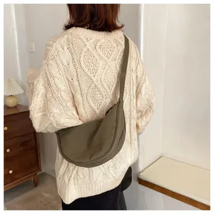 Olive green waterproof nylon half-moon crossbody bag shown on a model in a home setting
