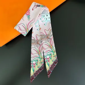Pink twilly silk scarf with elephant and tropical floral patterns on a luxury box