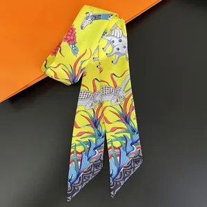 Macro detail of silk twilly scarf with yellow elephant and tropical plant prints
