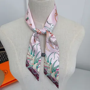 Detail of pink twilly scarf with elephant print and branding labels on a neck mannequin