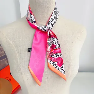 Detail of pink floral twilly scarf tied on a mannequin neck featuring letter prints
