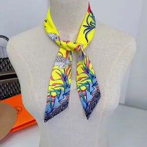 Detailed view of yellow silk scarf featuring intricate floral and elephant patterns