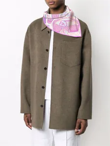 Dettaglio di un foulard di seta rosa a fiori indossato con un cappotto marrone