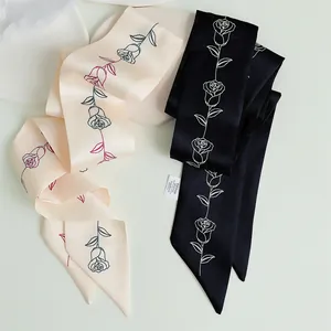 Dettaglio di sciarpe di seta con motivo a rose beige e nero su un vassoio elegante
