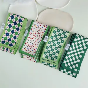 Détail de quatre foulards fins en soie verte et étiquettes sur une assiette blanche