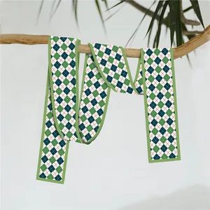 Foulard long à motif de losanges verts et bleus suspendu à une branche naturelle