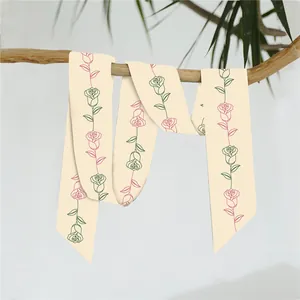 Elegante sciarpa di seta beige con motivi floreali appesa a un ramo di legno naturale