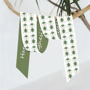 Pañuelo de seda verde con estampado de lirios del valle colgado de una rama natural