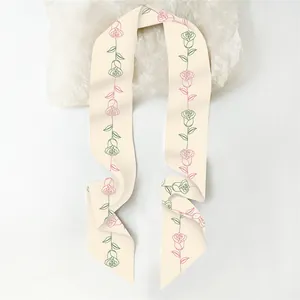 Dettaglio di un foulard in seta con motivi di rose rosa su fondo crema morbido