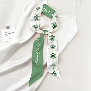 Detalle de pañuelo twilly verde con estampado de lirio de los valles en satén blanco