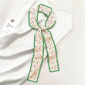 Détail d'un foulard en soie à fleurs avec bordure verte sur fond de tissu blanc élégant