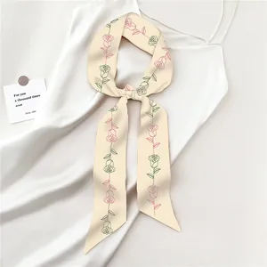 Dettaglio del twilly in seta con rose legato su un abito bianco per uno stile elegante