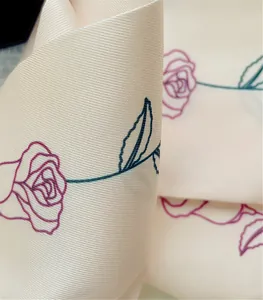 Dettaglio macro del motivo floreale rosa su nastro di seta che mostra trama e lucentezza