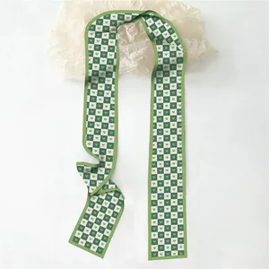 Gros plan du motif damier à cœurs verts sur un long foulard étroit en soie