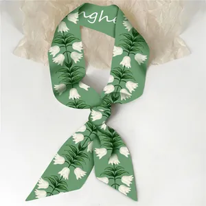 Detalle de pañuelo twilly verde con patrón de lirio de los valles y diseño de nudo