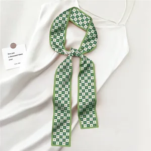 Détail du foulard étroit à damier vert avec motifs de cœur sur satin soyeux