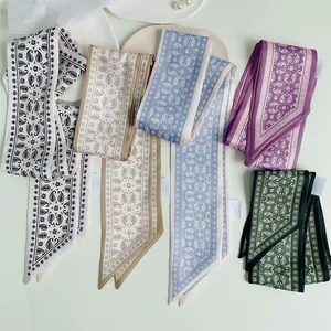 Detailed view of multiple paisley pattern silk twilly scarves with pointed ends and labels