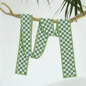Détail d'un motif à damier vert avec cœurs sur une longue écharpe en soie sur branche