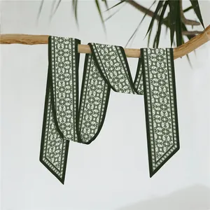 Elegant dark green paisley narrow silk scarf hanging on a natural wooden branch