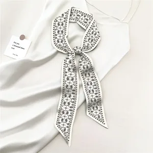 Close-up of white paisley print skinny silk scarf tied on a satin dress strap