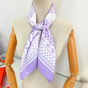 Close-up of French-style silk scarf with purple paisley and star patterns on mannequin