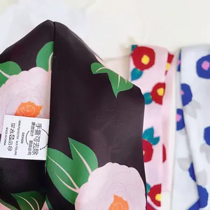 Detail of floral camellia print on black silk-like scarf with product care label