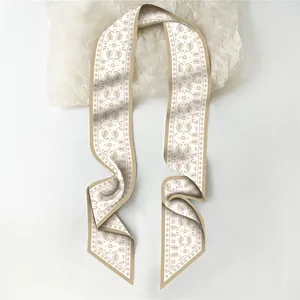 Close-up of a beige and brown paisley print long skinny scarf made of smooth faux silk