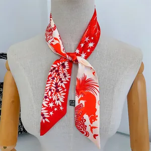 Close-up of a red and white silk scarf with animal prints tied as a stylish neck bow