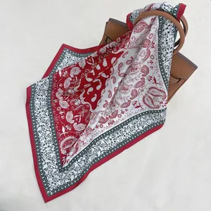 Red and white paisley twill silk scarf tied elegantly on a brown leather handbag