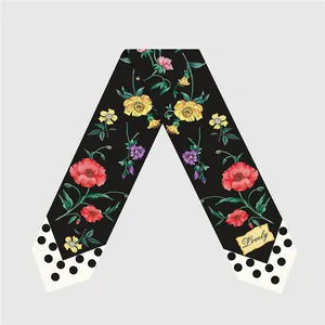Detalle de pañuelo twilly negro con flores y extremos de lunares con texto Lovely