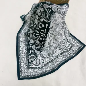 Detailed view of a black and white paisley silk scarf draped on a woven basket