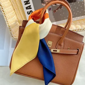 Sac à main en cuir marron avec boucle dorée et foulard décoratif coloré sur l'anse