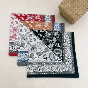 Close-up of three paisley patterned silk scarves in red, coffee and black on a textured cloth