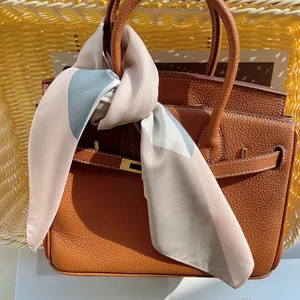 Foulard en soie aux motifs colorés élégamment enroulé sur la poignée d'un sac en cuir marron