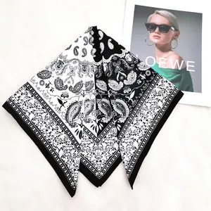 Close-up of a black and white paisley print twill silk scarf on a textured surface
