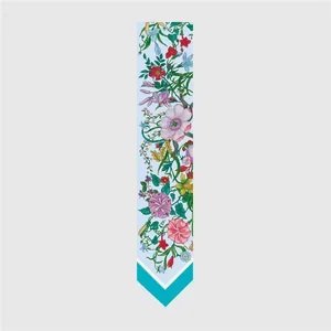 Detalle de pañuelo de seda azul claro con estampado floral colorido y dobladillo en forma de V