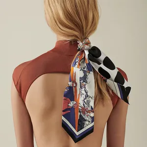 Detalle de un pañuelo de seda con estampado floral y animal y un anillo de metal