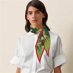 Detail of floral green silk scarf with red edges styled on a white shirt neck