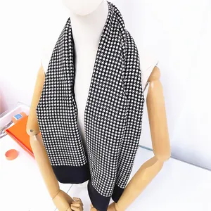 Macro detail of houndstooth wool scarf with black border and luxury packaging