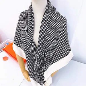 Detail of classic houndstooth warm large square scarf draped on mannequin with gift box