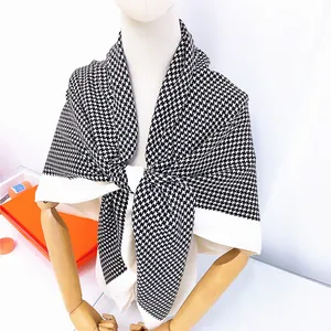 Detail of black and white houndstooth scarf draped with classic orange gift box
