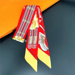 Detail van rode polyester twilly sjaal met ruitersprint op iconische oranje doos